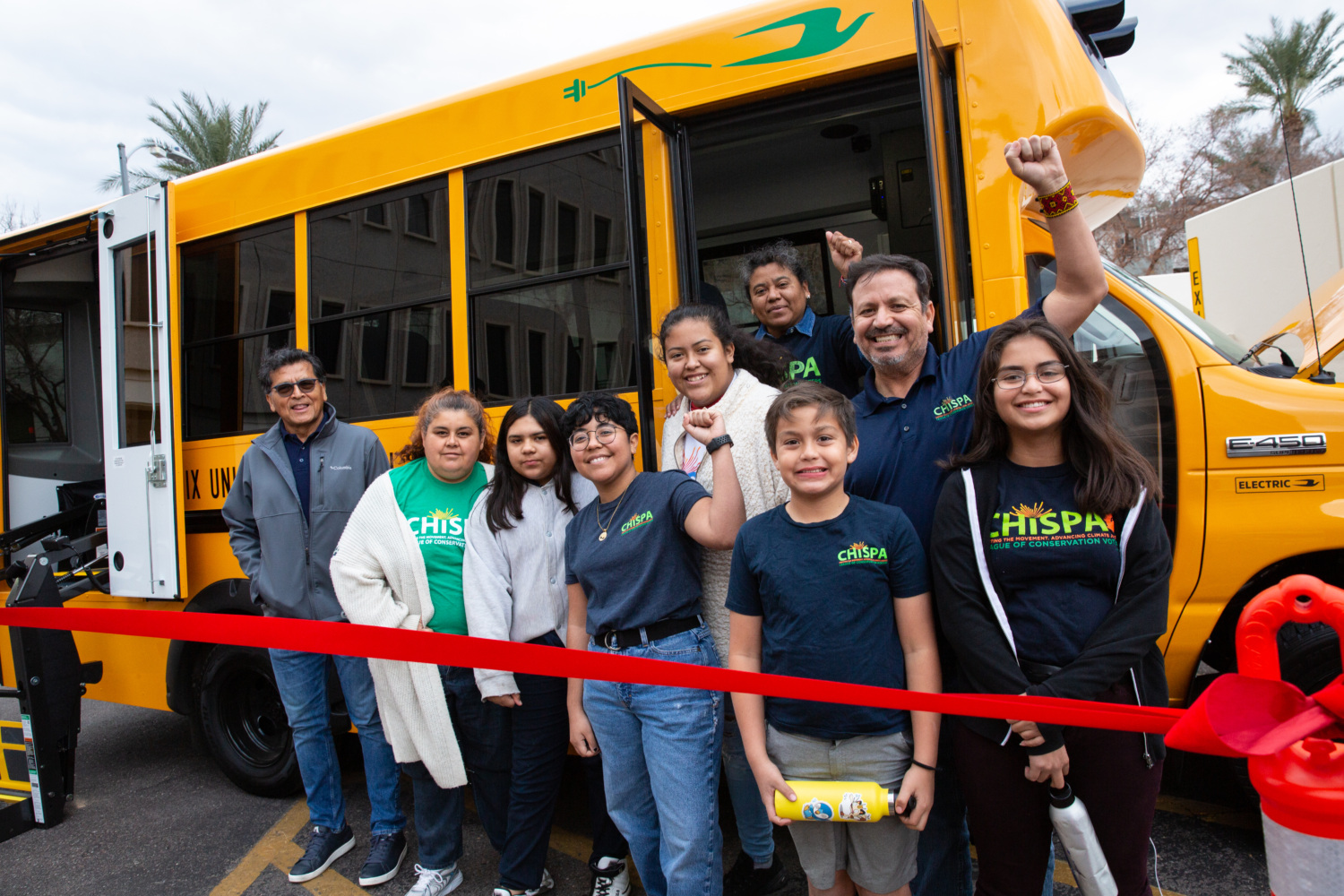 Chispa activists celebrating in front of an electric school bus.