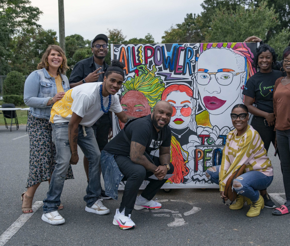 A group of North Carolina community organizers posing with a mural celebrating National Civic Engagement Week