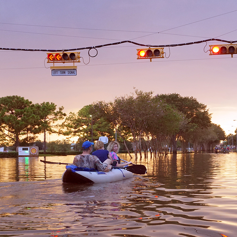 People kayaking through flooded streets of Houston.