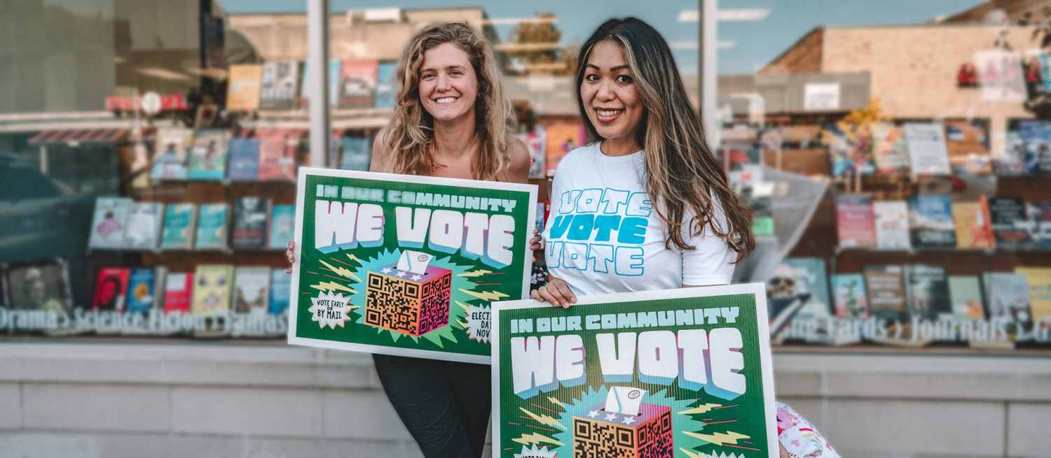 Two people holding signs in front of a bookstore.