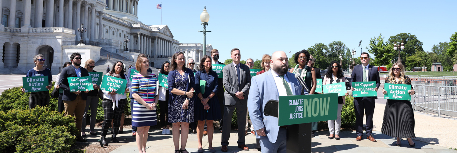 Group of people doing a press event in front of the U.S. Capitol building.