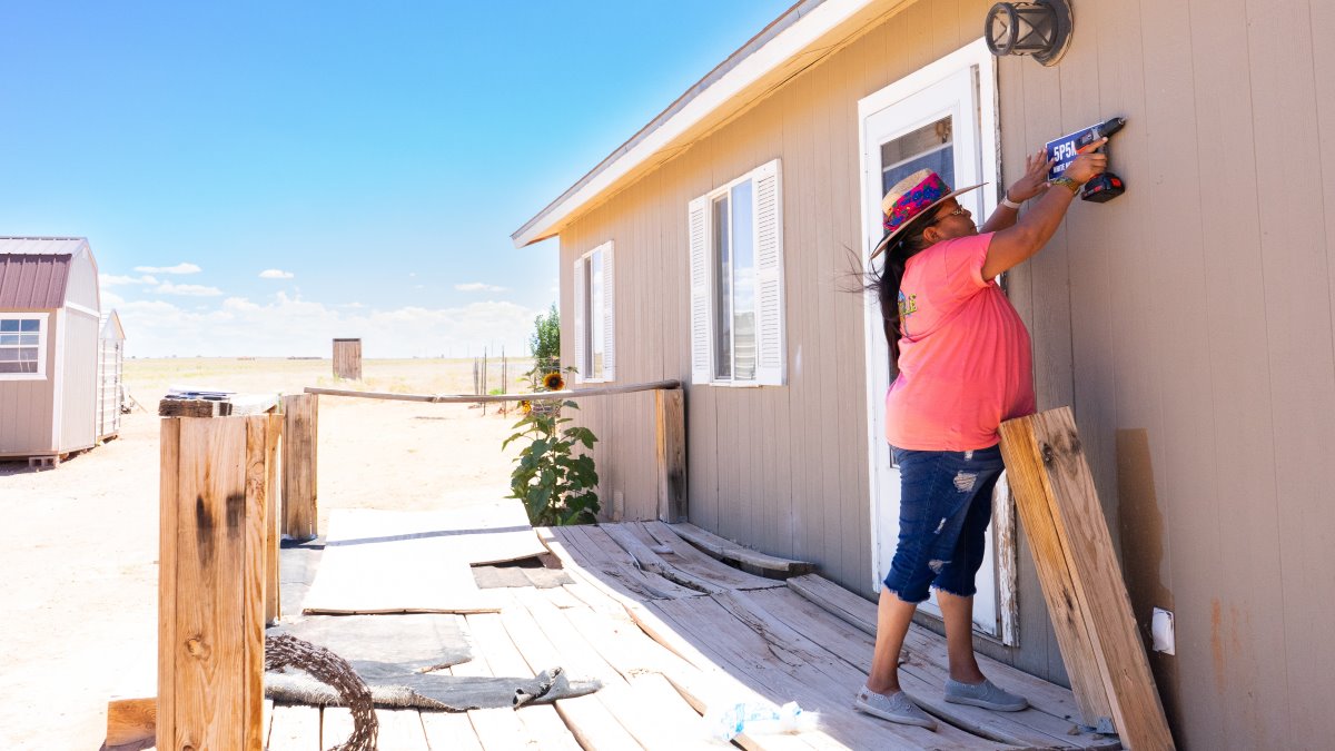 At a house in the Utah desert, a woman installs an address sign next to the front door.