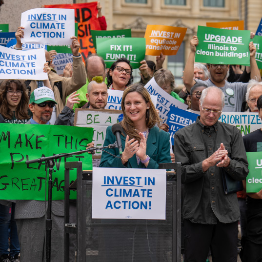 Activists in Illinois gather with signs at a podium calling for investments in climate action