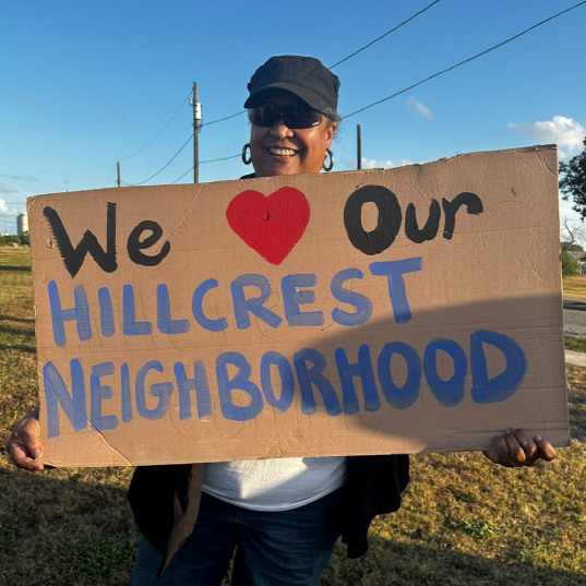 Monna Lytle holds up a sign that reads "we love our Hillcrest neighborhood"